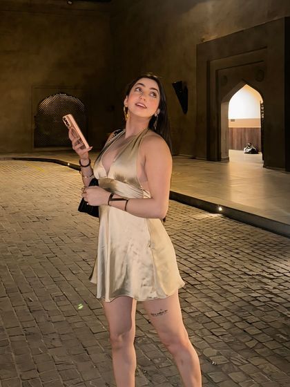 Posing in a golden satin mini dress in the stunning driveway of the Fairmont Jaipur. This is a perfect example of high-end resort wear styling.