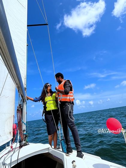 The couple posing by the sail of the yacht, enjoying the beautiful weather and their special moment.