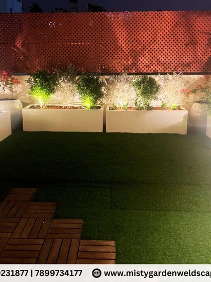 The night lighting brings this terrace garden to life. Spotlights in the planters highlight the foliage against the dark red PVC lattice, creating a dramatic and beautiful effect.