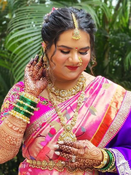 This bride is radiating elegance in her pink and purple Paithani saree. The makeup is soft and glowing, with beautiful henna and traditional green bangles completing the look.
