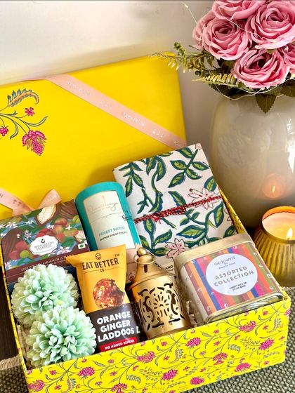 A bright yellow box holds this unique Diwali hamper, which includes granola bars, dhoop sticks, a handcrafted diary, a decorative lamp, and a jar of Goodwyn tea bags. It's a gift that encourages mindfulness and relaxation.