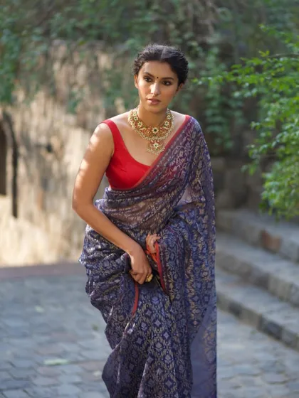 A simple yet powerful styling choice. We paired this deep blue Banarasi saree with a statement gold necklace and a contrasting red blouse, proving that sometimes one perfect piece is all you need.