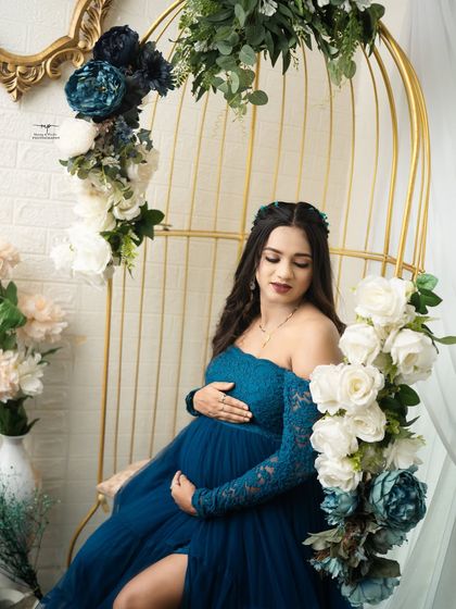 A quiet moment of reflection for the gorgeous mommy-to-be. Dressed in a deep teal gown, she is surrounded by a beautiful arrangement of blue and white flowers.
