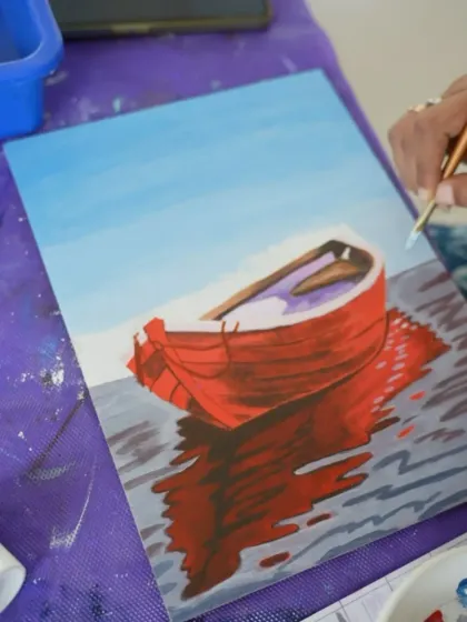 A close-up of a student's acrylic painting of a boat, showing beautiful reflections on the water.