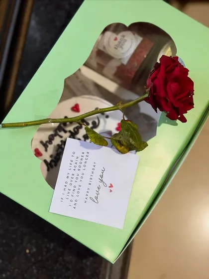 A romantic birthday package showing a bento cake and cake jars inside a gift box, complete with a single red rose and a heartfelt "love you" note.