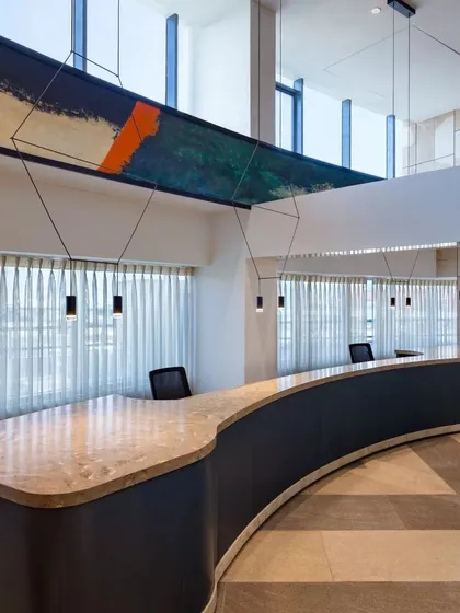 The reception area at Conscient One, where a hand-painted beam serves as a dramatic art piece above the curved desk. This design blends artistic expression with functional elegance.