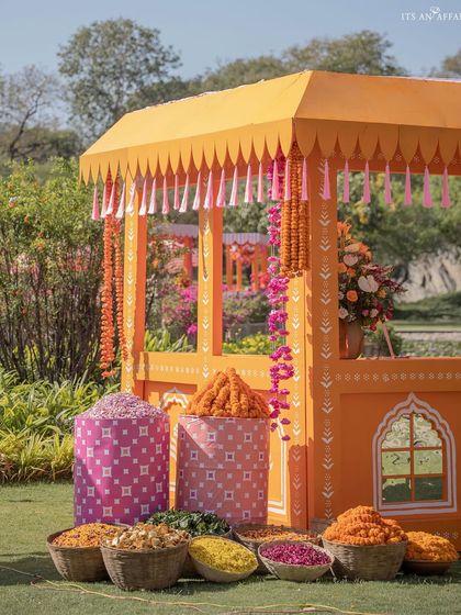 A traditional flower stall, or 'phoolon ki theli', decorated in bright orange and filled with baskets of marigolds and other flowers for the Haldi ceremony.