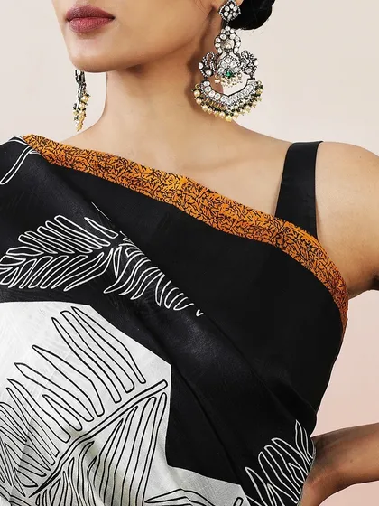 A close-up of the one-shoulder blouse and the delicate orange border of the saree.