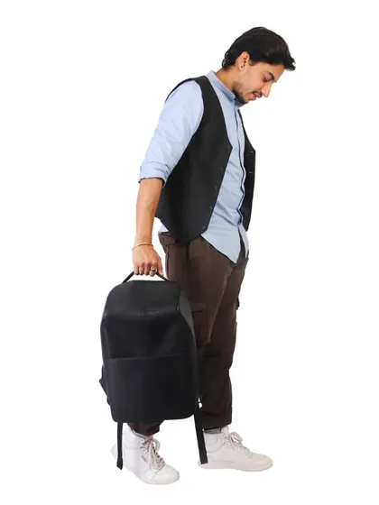 A male model holding a black backpack. On-model shots for accessories like bags help customers understand the product's size and how it's carried.