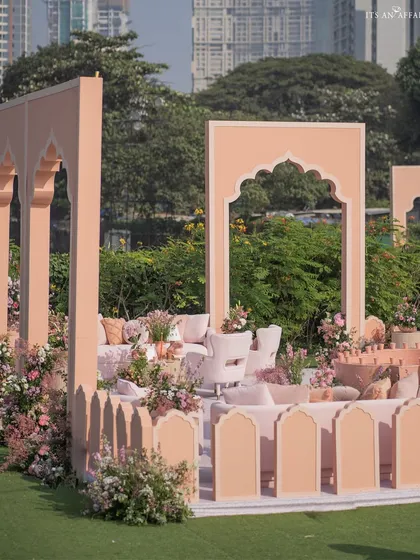 The hand-painted structures create distinct zones for seating, surrounded by lush greenery and floral arrangements.