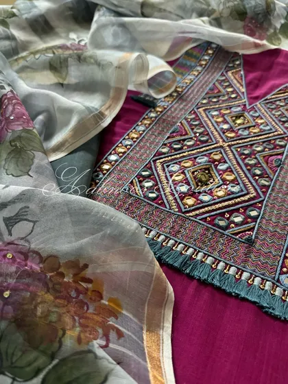A detailed shot focusing on the intricate mirrorwork and thread embroidery of the kurta's yoke, set against the soft floral print of the dupatta.