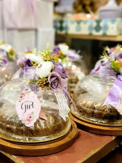 Announcing a new arrival is such a joyous occasion, and we love creating the perfect favors to share the news. These "It's a Girl" announcement gifts feature individual cakes under glass cloches, each adorned with delicate purple flowers, lace ribbons, and a personalized floral tag. It's a sweet and elegant way to celebrate your new bundle of joy.
