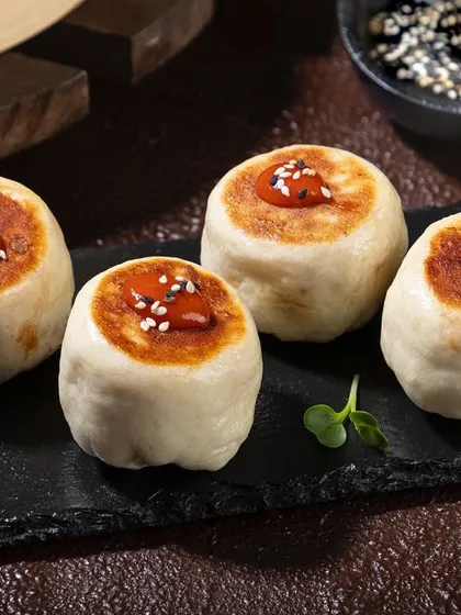 Pan-fried buns with a dollop of chili sauce. The dark, moody lighting and slate serving platter give these a gourmet look.