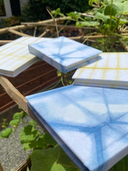 A set of my tie-dyed notebooks resting on a bamboo branch. The blue is from natural indigo and the yellow from marigold flowers, bringing the colours of nature to your writing.