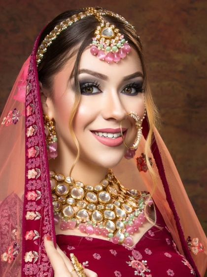 A smiling bride wearing a Polki necklace with large pink stones. This is a cheerful and beautiful option for a day wedding or mehendi.