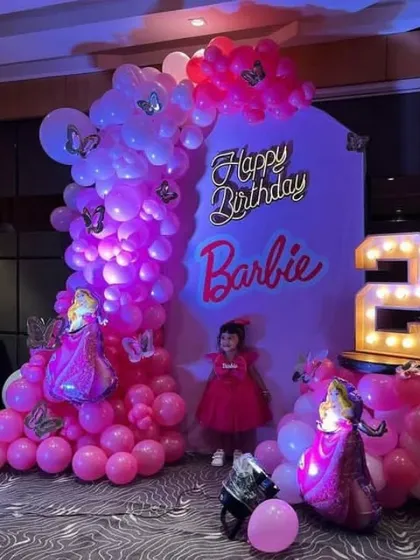 A glamorous Barbie-themed second birthday party. The decor is all pink with a custom backdrop, balloon arch, and a '2' marquee light.