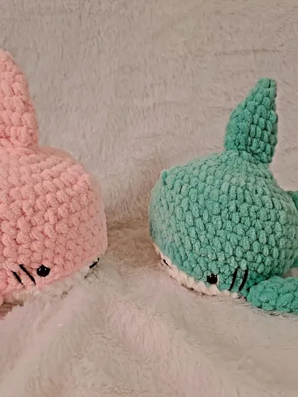 A pair of plush sharks in pink and mint green.