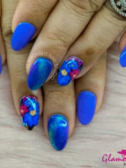 Make a statement with this electric blue set. We paired solid blue nails with accent nails featuring a galaxy of hand-painted flowers in pink, yellow, and blue, creating a vibrant and artistic look.