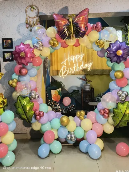 A whimsical garden theme for a 4th birthday. This home setup features a pastel balloon ring decorated with large butterfly and flower foil balloons, and a gold foil number '4'.
