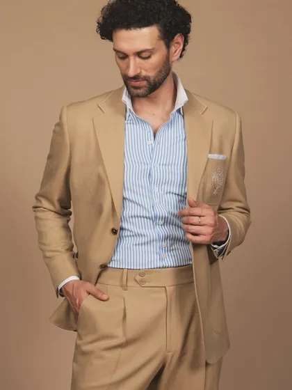 A different view of the tan suit, paired with a striped blue and white shirt. This combination showcases a timeless, preppy-inspired professional style.