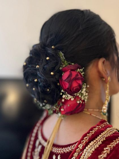 A romantic bridal bun with deep red roses and baby's breath, accented with tiny gold beads for a touch of sparkle.