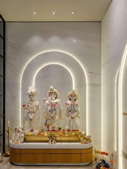 We create tranquil sacred spaces that blend modern design with traditional reverence. This pooja room features elegant white marble walls with arched, back-lit panels that create a serene glow. The custom wooden base provides a warm, natural element, resulting in a peaceful corner for prayer and reflection.