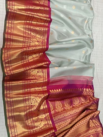 A pastel grey-green pure Gadwal silk handloom saree with a vibrant red and pink traditional border.