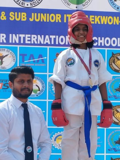 A female student stands proudly on the podium after her sparring event.