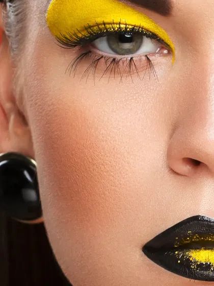 A close-up on the eye and cheek, showcasing the dramatic yellow eyeshadow and flawless skin. This macro beauty shot highlights the makeup artist's skill and the quality of the products.