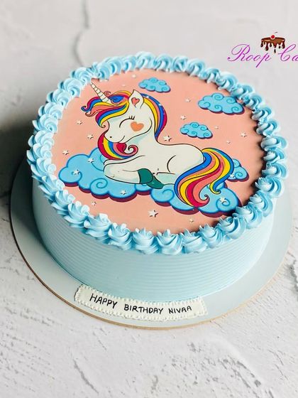 A sweet and simple unicorn cake. This half-kg design features an edible print of a cute unicorn sleeping on a cloud, surrounded by a piped blue border.