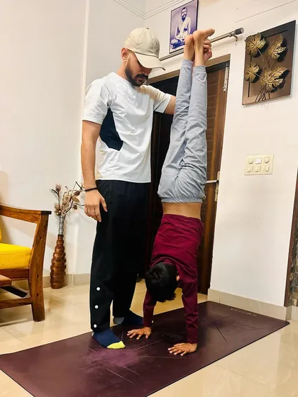 Inverting the ordinary. Assisting a young student with a handstand, focusing on building shoulder strength and core engagement for a stable and controlled pose.
