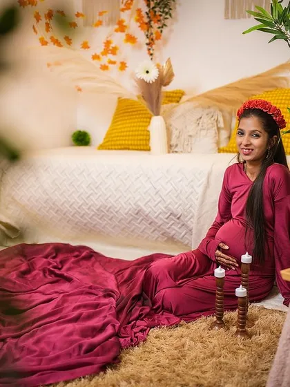 A peaceful maternity portrait in our cozy boho setup. The client is seated comfortably in a deep red gown, creating a warm and intimate atmosphere for her solo shoot.