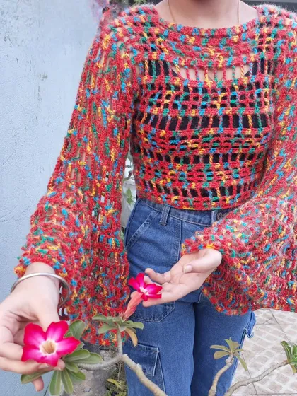 This is the Bell Baby Mesh Top, a vibrant and airy pullover with dramatic bell sleeves. The multi-colored yarn creates a beautiful, confetti-like effect.