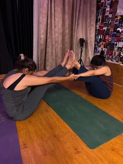 Working together in a partner boat pose (Navasana). This not only challenges core strength but also requires balance and coordination between partners.
