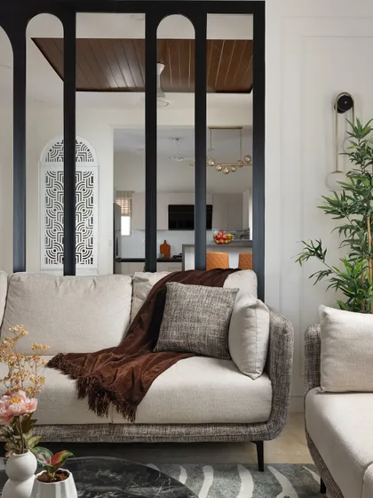 A view from the living room sofa, looking past the arched metal partition towards the dining area and kitchen. This design choice maintains an open feel while creating distinct functional zones.