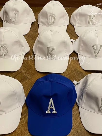 Shine bright with these blinged-out caps. Available in white and blue, these baseball caps feature rhinestone-studded initials for a touch of sparkle.