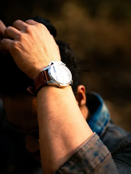 A close-up, abstract shot focusing on the watch and the model's hand. These details help to build a complete character story.