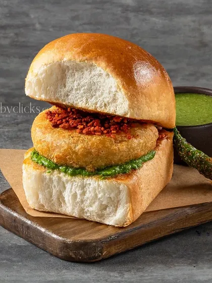 A close-up of a Vada Pav from The Canteen Project, showing the layers of chutney and the potato filling.