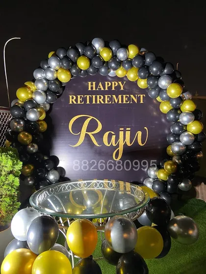 This angle shows how the retirement decoration integrates with other party elements, like a cake table. The loose balloons on the floor add to the festive atmosphere.