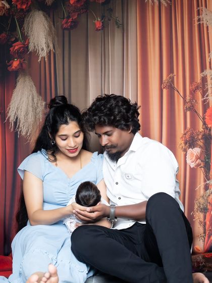 A tender moment as new parents gaze down at their newborn, cupping the baby's head in their hands.