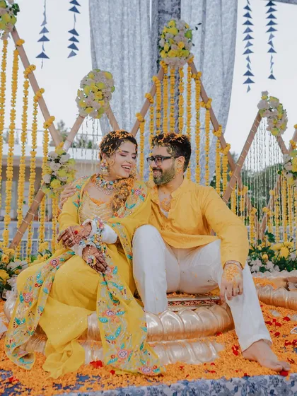 The couple sharing a happy moment on their Haldi stage, surrounded by beautiful marigold decorations.
