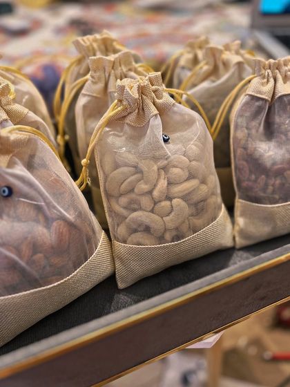 A closer look at the sheer jute potlis filled with high-quality nuts. The tiny evil eye bead on the drawstring is a subtle but meaningful touch that reinforces the theme throughout the entire collection.