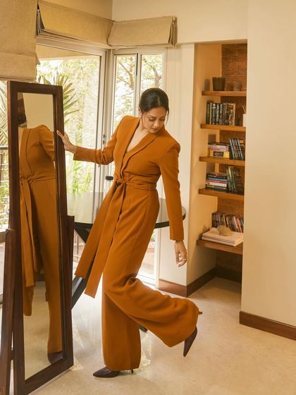 Jyotika in a custom-designed burnt orange jumpsuit with a matching longline jacket, a bold and stylish choice for a Netflix event.