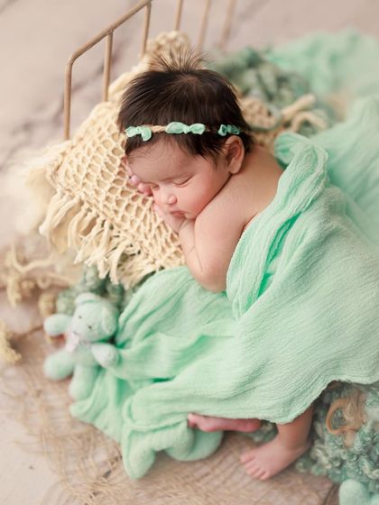 A dream-like pose on a tiny bed. The flowing mint green fabric and matching headband create a soft and ethereal feel.