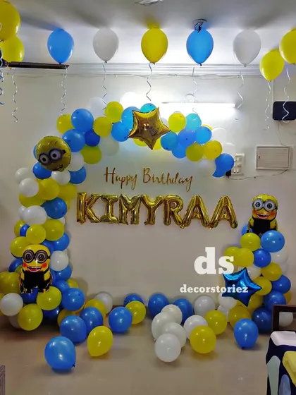A fun Minion-themed birthday party setup. This decoration uses the signature blue and yellow colors for the balloon arch, with Minion character foils and a personalized name banner.