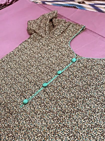 A simple printed suit is elevated with contrasting turquoise piping and matching potli buttons on the neckline.