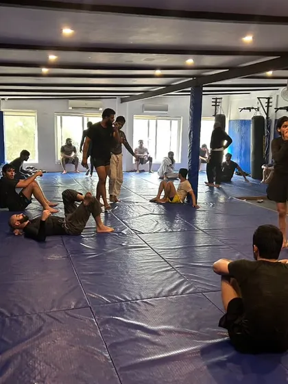 The mat is a space for learning and growth. Here, students are scattered across the gym, some rolling, some resting, and some discussing techniques after a round.