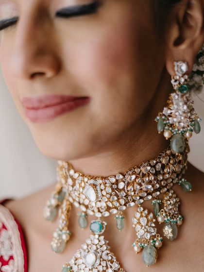 A detailed close-up of the bride's jewelry and eye makeup. The soft green in her necklace is subtly echoed in her look, creating a cohesive and polished feel.