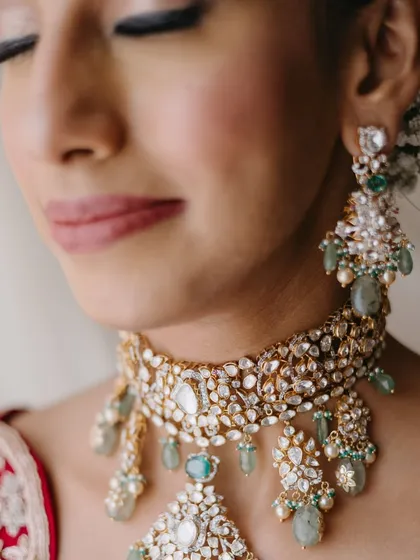 A detailed close-up of the bride's jewelry and eye makeup. The soft green in her necklace is subtly echoed in her look, creating a cohesive and polished feel.