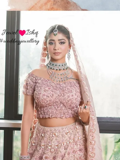 A glamorous bridal look featuring a stunning layered diamond and emerald necklace set against a delicate pink lehenga. This is for the bride who wants to feel both romantic and regal.